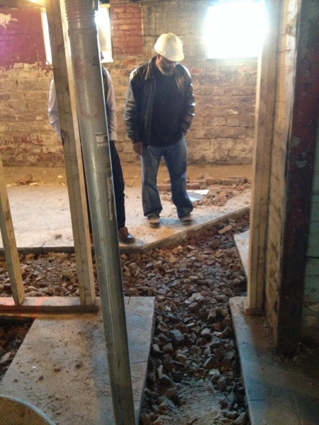 Keith Owens looking at cuts into the basement floor for drains. Rubble from previous residences on the property fill the area.