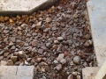 A cut-out in the floor for drain pipe placement. The rubble is evidence of other buildings that previously occupied this site.